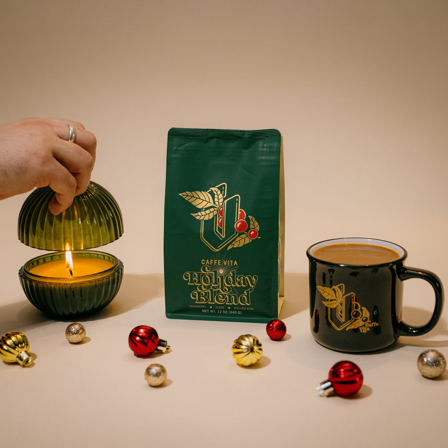 12oz Holiday Bag next to candle and mug of coffee with ornaments scattered in the foreground. 