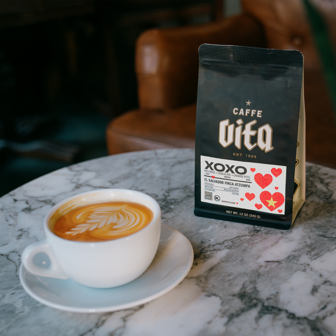 12oz bag of XOXO next to latte on a cafe table. 