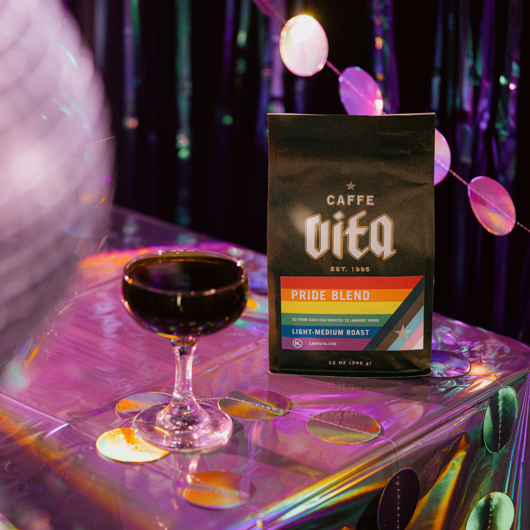 12oz pride blend bag with coupe of cold brew on shimmery surface. Disco ball in foreground. 